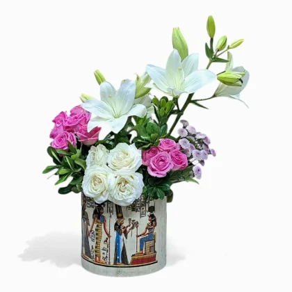 باقة "أناقة النيل" من لافيولا مع زنابق بيضاء وورود وردية ناعمة في مزهرية على طراز ورق البردي مزينة بنقوش فرعونية لتقديم الزهور الملكية، احتفاءً بالتناغم بين الفن والطبيعة في مصر القديمة.