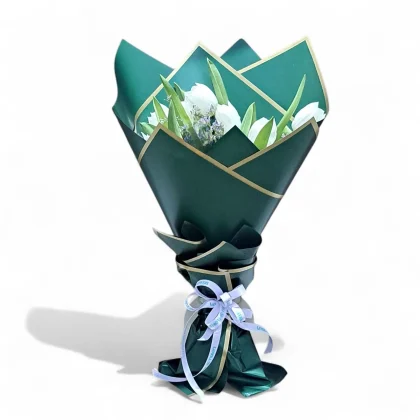 White tulip bouquet wrapped in emerald green paper with golden edges