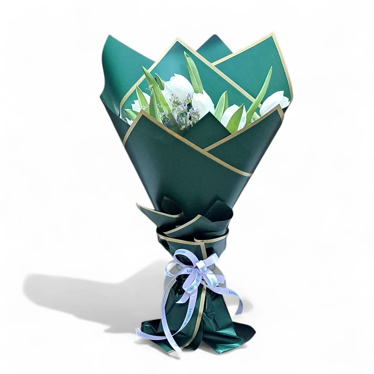 White tulip bouquet wrapped in emerald green paper with golden edges